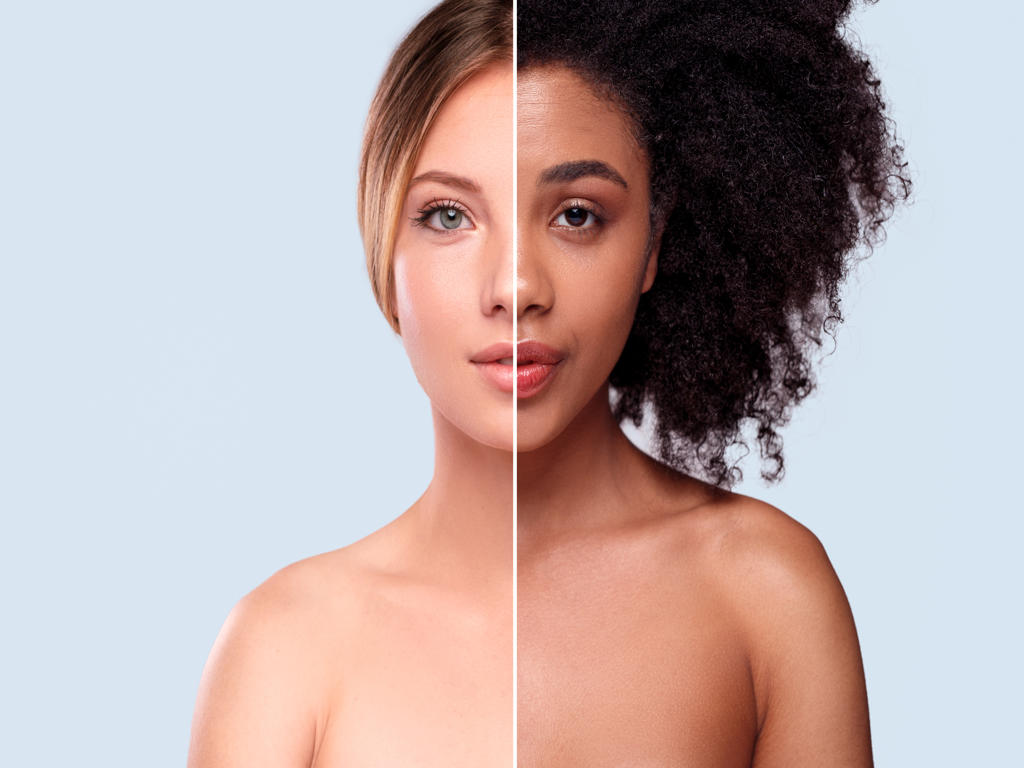 Halves of beautiful Caucasian and African ladies combined to show multiracial difference against gray background