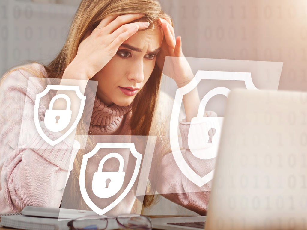 Digital security problem and access ban. Upset woman holds her head with hands and looks at computer, double exposure with holographic abstract symbols of closed locks and digital code, collage